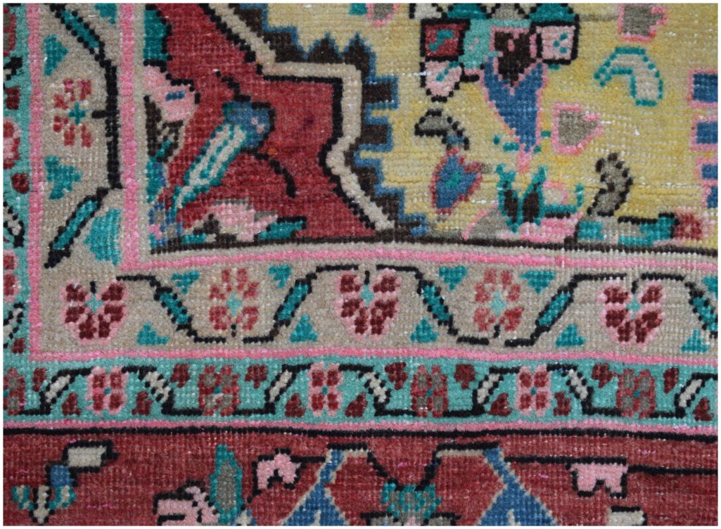 A close-up of a vintage Persian rug featuring intricate floral patterns in red, yellow, and teal.