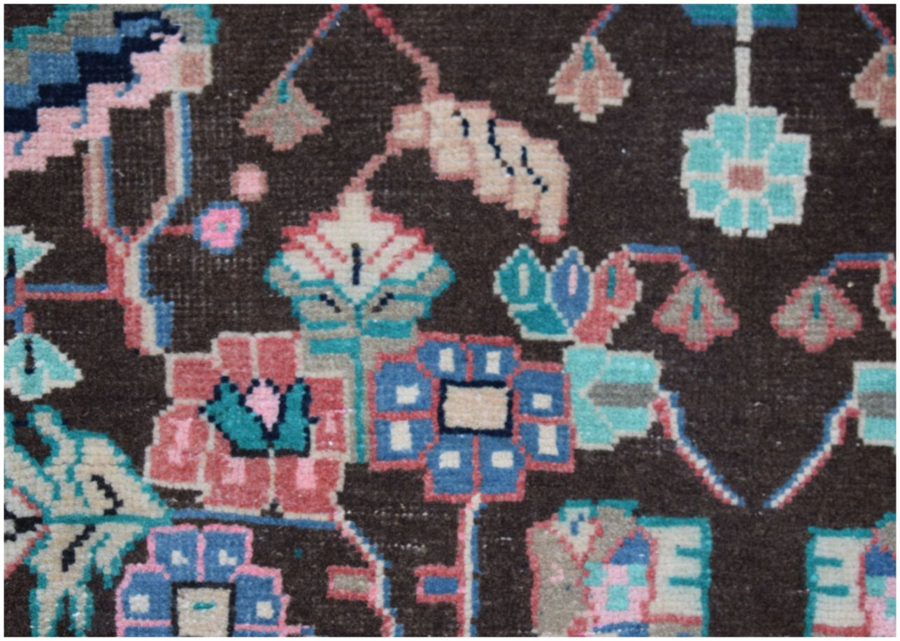 A close-up of a vintage Persian rug featuring intricate floral patterns in pink, blue, and cream.