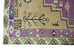 A vintage Persian rug featuring geometric patterns in purple, beige, green, and blue.