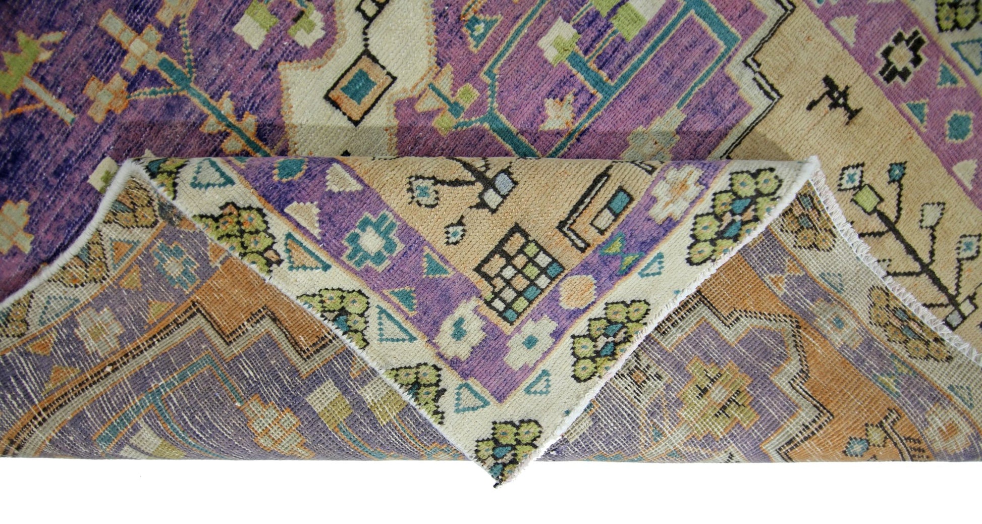 A vintage Persian rug with a geometric pattern in purple, orange, and cream tones.