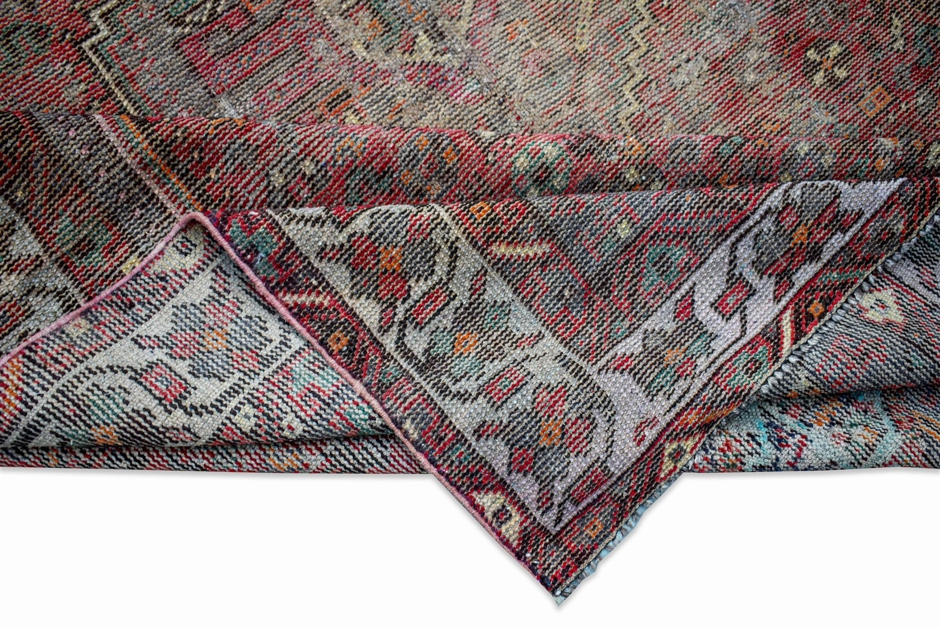 A folded vintage Persian rug featuring intricate patterns in red, grey, and blue tones.