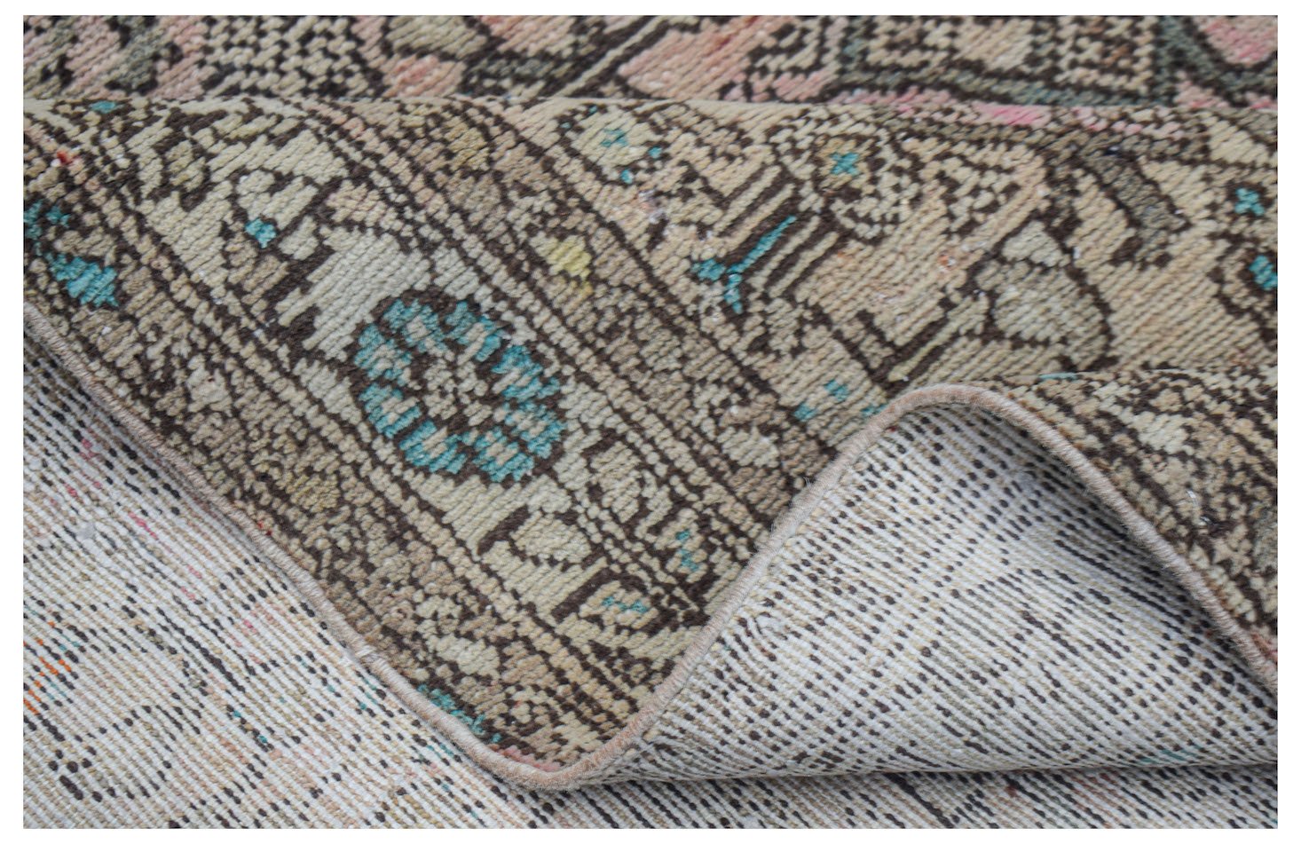 A handwoven vintage Persian rug with a worn, patterned wool pile and a visible cotton foundation.