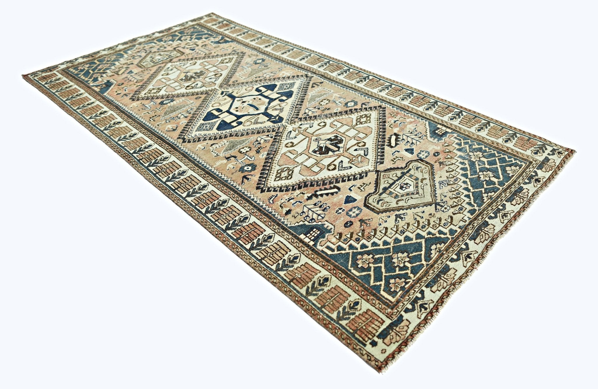 A vintage handmade Persian rug featuring geometric diamond patterns in blue and beige tones.