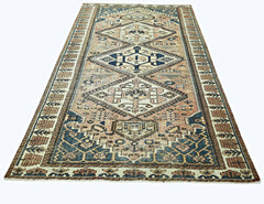 A vintage Persian rug featuring a geometric diamond pattern in shades of blue and tan.