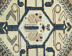 A vintage Persian rug featuring a geometric blue and cream medallion pattern.