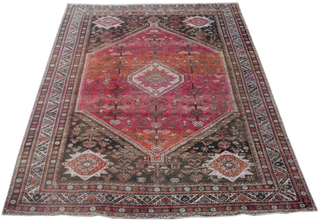 A handmade vintage Persian wool rug featuring a central diamond medallion in red and orange tones.