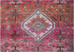 A handmade vintage Persian wool rug featuring a central diamond medallion on a vibrant pink field.