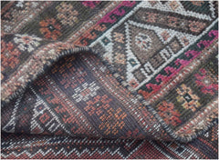 A folded corner of a handmade vintage Persian wool rug featuring intricate tribal patterns.