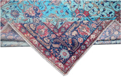 A vintage Persian rug with a folded corner revealing a blue and red floral pattern.