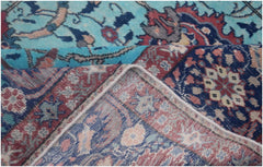 A folded vintage Persian rug featuring intricate floral patterns in blue, red, and cream tones.