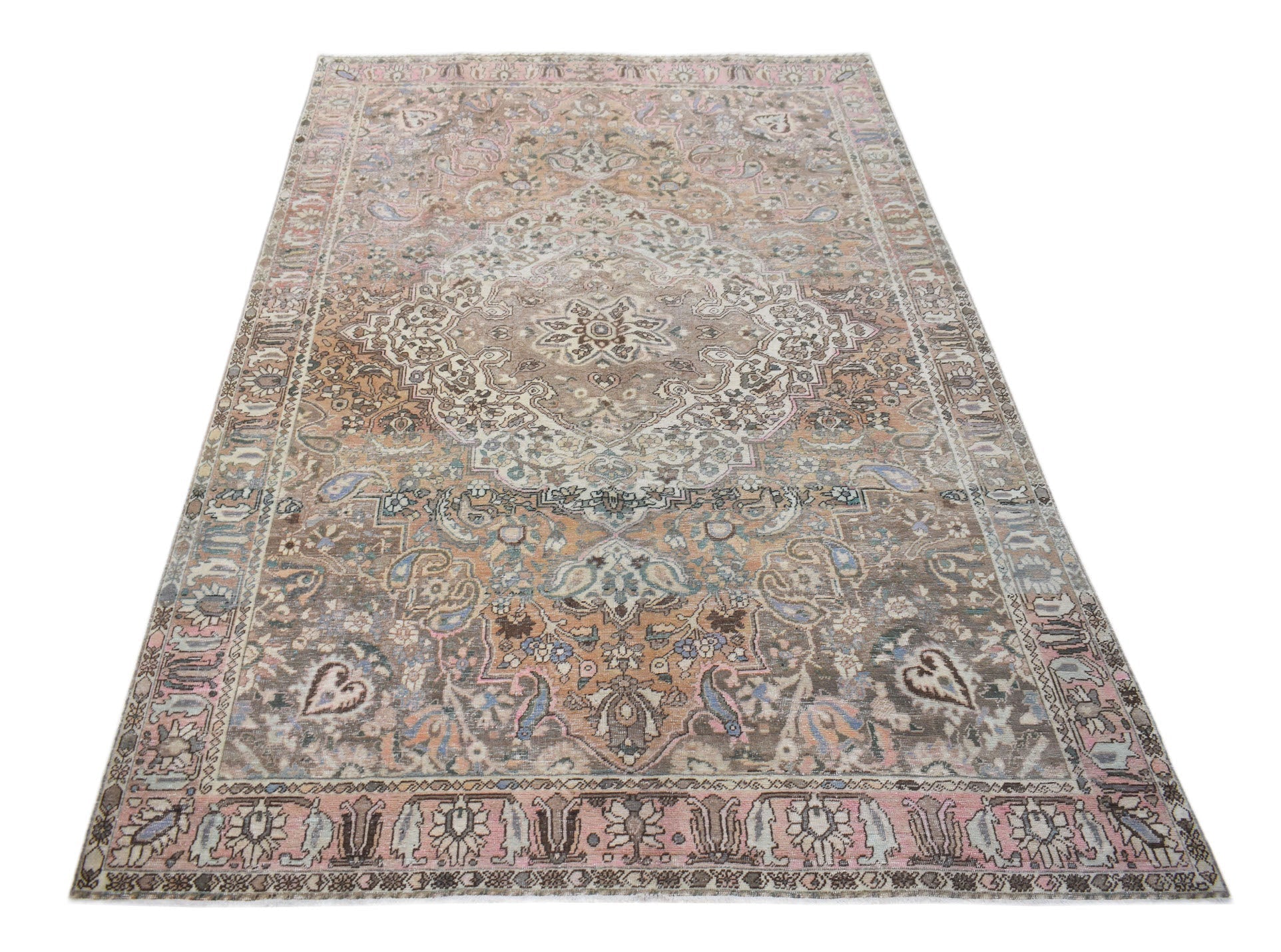 A vintage handwoven Persian rug featuring a central medallion in muted brown, pink, and blue tones.