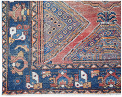 A handwoven vintage Persian rug featuring geometric patterns in red, blue, and orange tones.