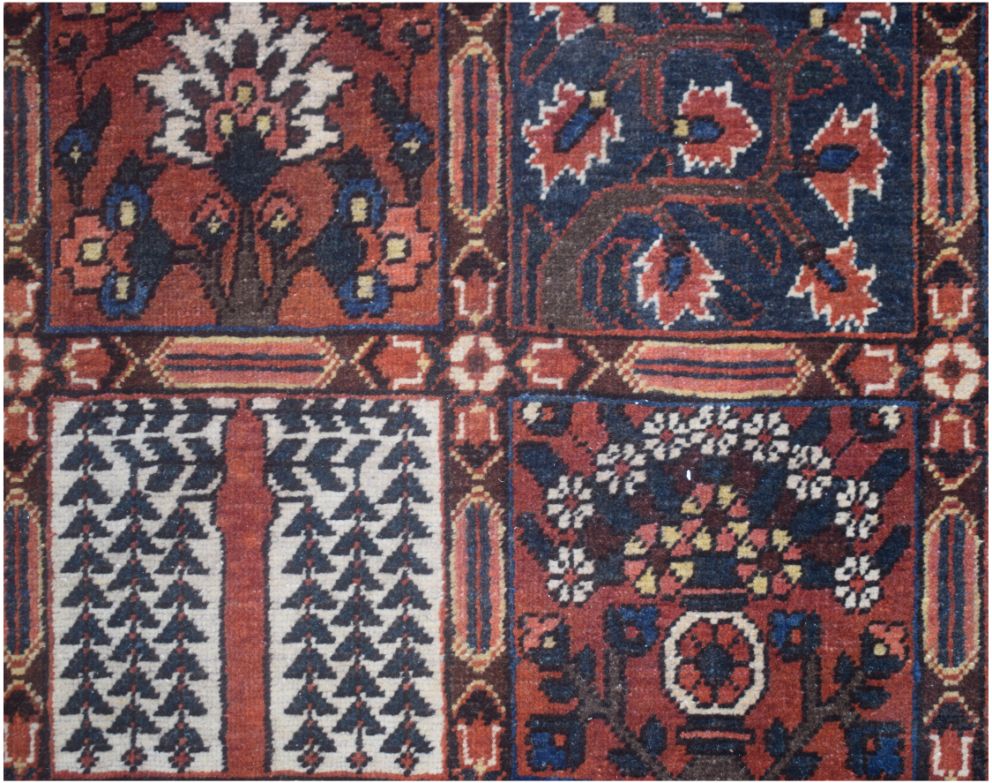 A vintage Persian rug featuring a geometric grid pattern with floral and tree motifs.