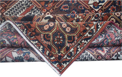 A folded vintage Persian wool rug featuring intricate tribal patterns in red, blue, and cream.
