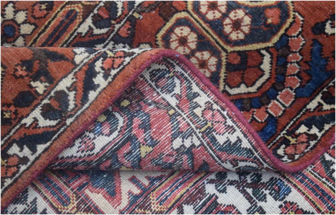 A corner of a handmade vintage Persian wool rug is folded back to show its woven cotton backing.