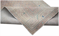 A handwoven vintage Persian rug featuring a faded pink and beige pattern with blue accents.