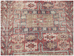 A vintage handwoven Persian rug featuring a geometric pattern in red, blue, and cream tones.