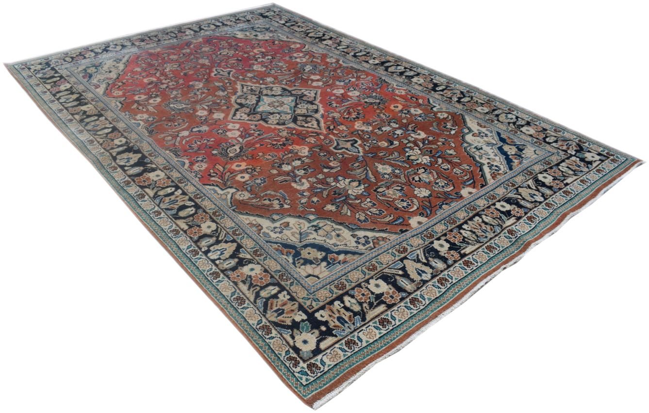 A vintage handmade Persian wool rug featuring a central medallion on a red floral field.