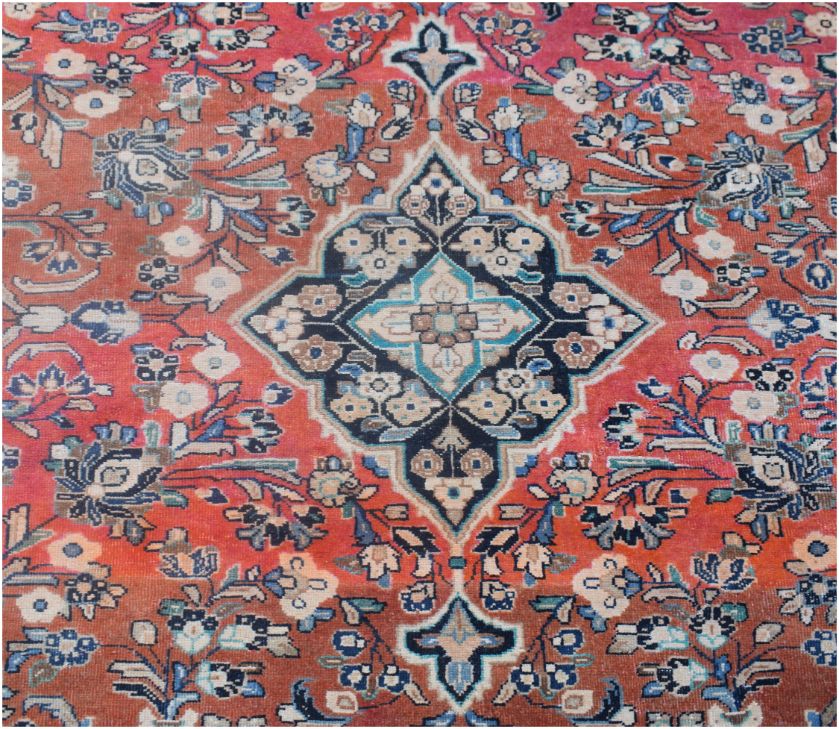 A vintage Persian rug featuring a central floral medallion on a red field with intricate patterns.