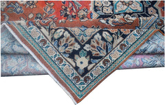 A folded vintage Persian wool rug featuring a dark blue corner medallion and orange accents.