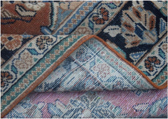 A folded vintage Persian wool rug featuring intricate floral patterns in blue, orange, and cream.