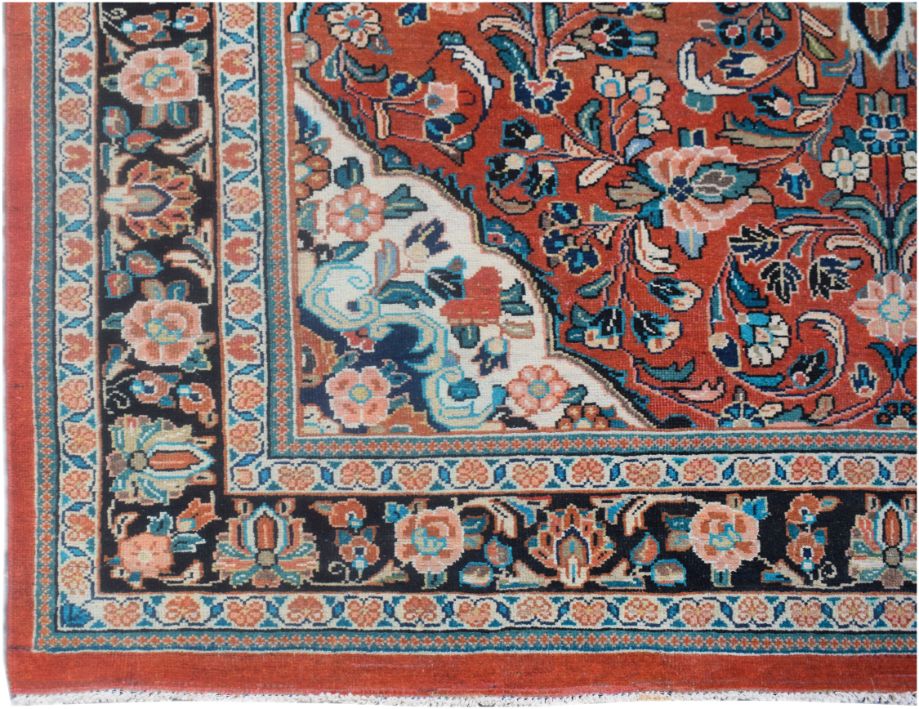 A vintage Persian rug featuring a floral pattern in red, black, and cream tones.