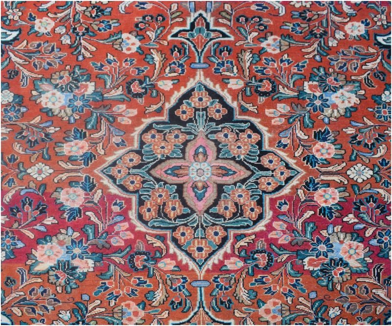 A vintage Persian rug featuring a central floral medallion on a red field with intricate patterns.