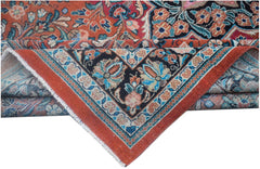 A folded vintage Persian rug featuring intricate floral patterns in red, blue, and black.