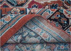 A corner of a handmade vintage Persian wool rug is folded back to reveal its woven underside.