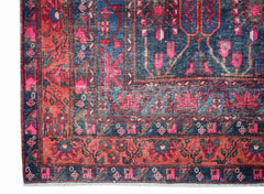 A vintage handwoven Persian rug featuring a floral pattern in shades of blue and pink.