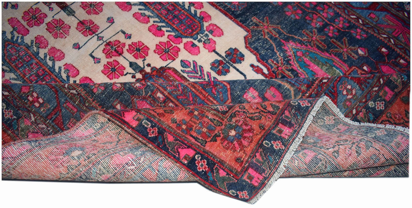A handwoven vintage Persian rug featuring a floral pattern in shades of pink, blue, and cream.