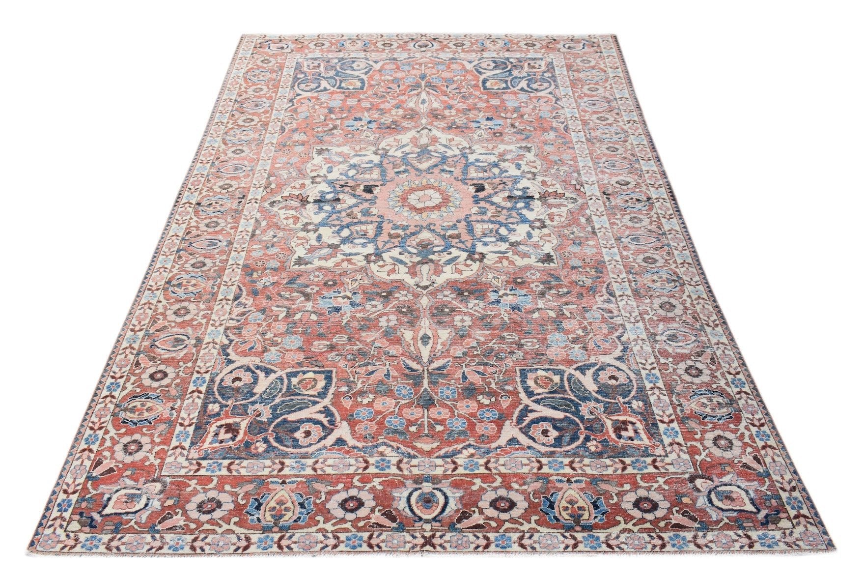 A vintage handwoven Persian rug featuring a floral medallion pattern in faded red and blue tones.