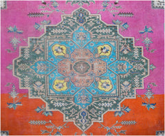 A vintage Persian rug featuring a central geometric medallion in blue, green, and yellow on a pink and orange background.
