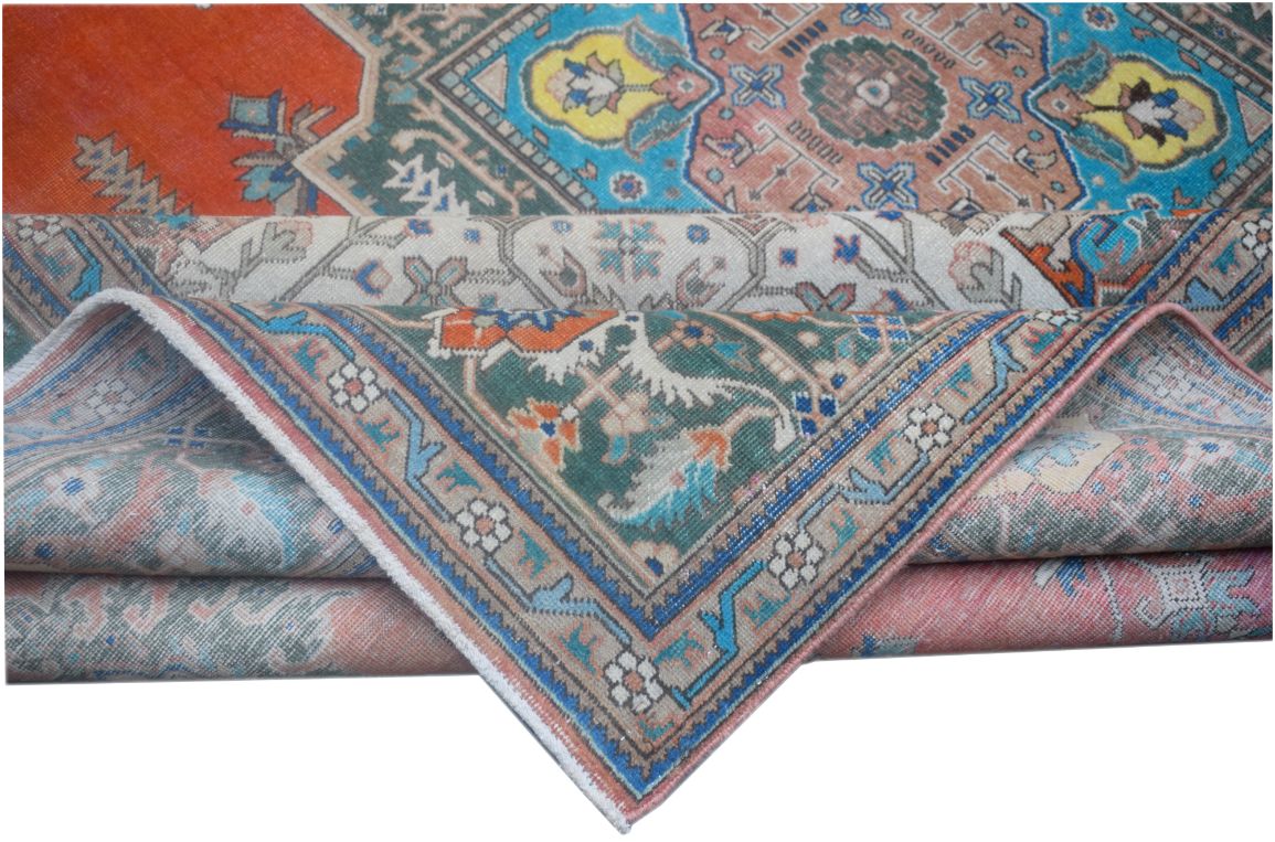 A folded vintage Persian wool rug featuring intricate tribal patterns in blue, orange, and green.