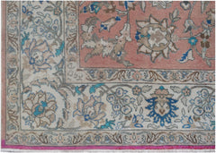 A vintage Persian wool rug featuring a floral pattern in shades of pink, blue, and cream.