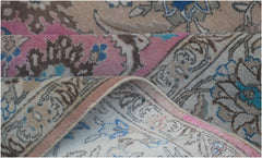 A close-up of a vintage Persian wool rug featuring intricate floral patterns in pink and blue.