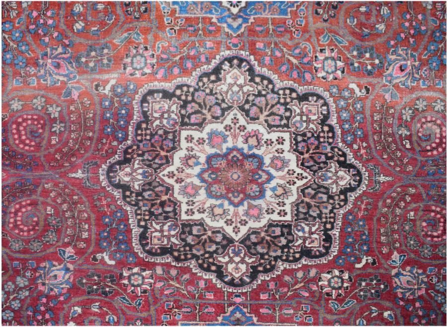 A vintage Persian rug featuring a central floral medallion on a red field with intricate patterns.