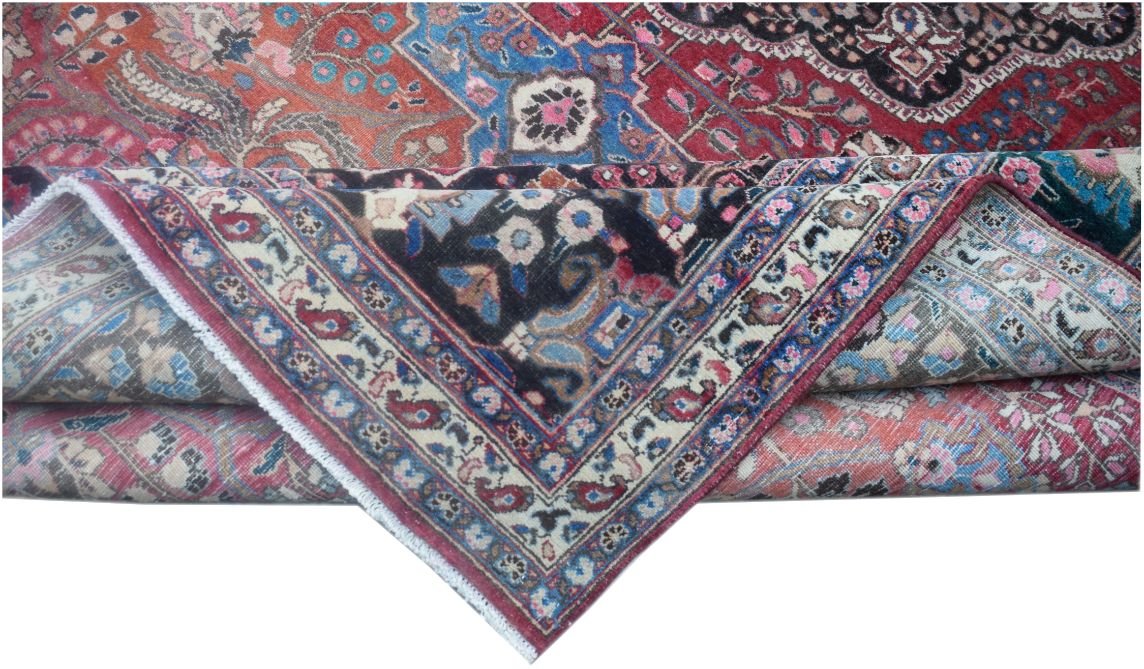 A folded vintage Persian wool rug featuring intricate floral patterns in red, blue, and black.