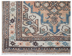 A handwoven vintage Persian runner featuring a geometric pattern in muted orange, blue, and cream.
