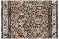A vintage Persian runner featuring a geometric pattern in shades of orange, brown, and green.