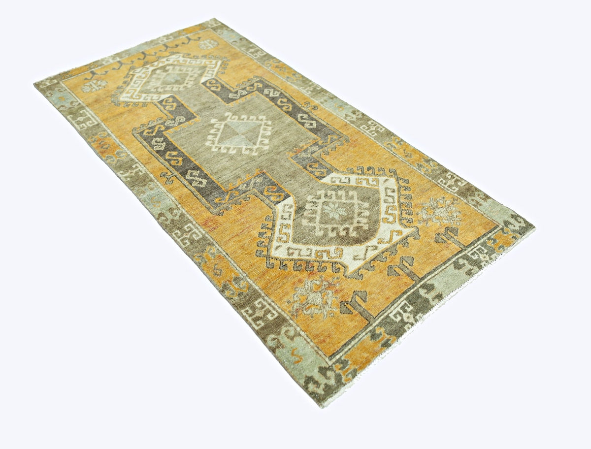 A vintage Persian runner rug featuring a geometric pattern in shades of orange, grey, and cream.