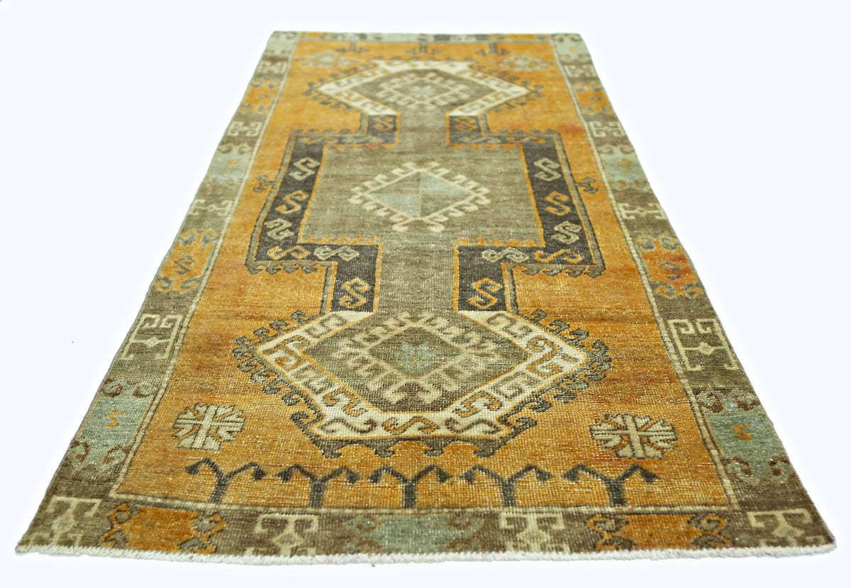 A vintage Persian runner rug featuring geometric patterns in shades of orange, brown, and grey.