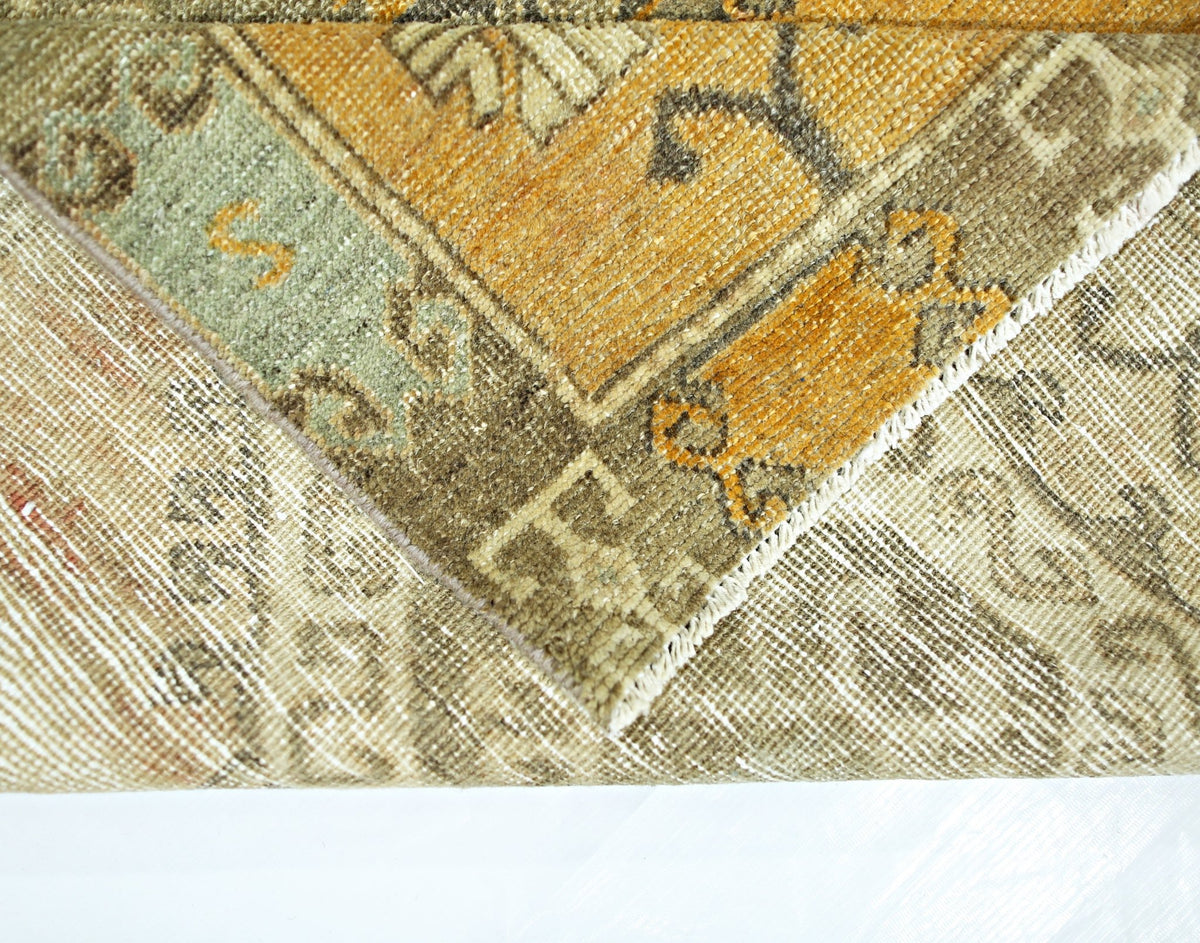 A close-up view of a vintage Persian runner showing its wool pile, cotton base, and worn texture.