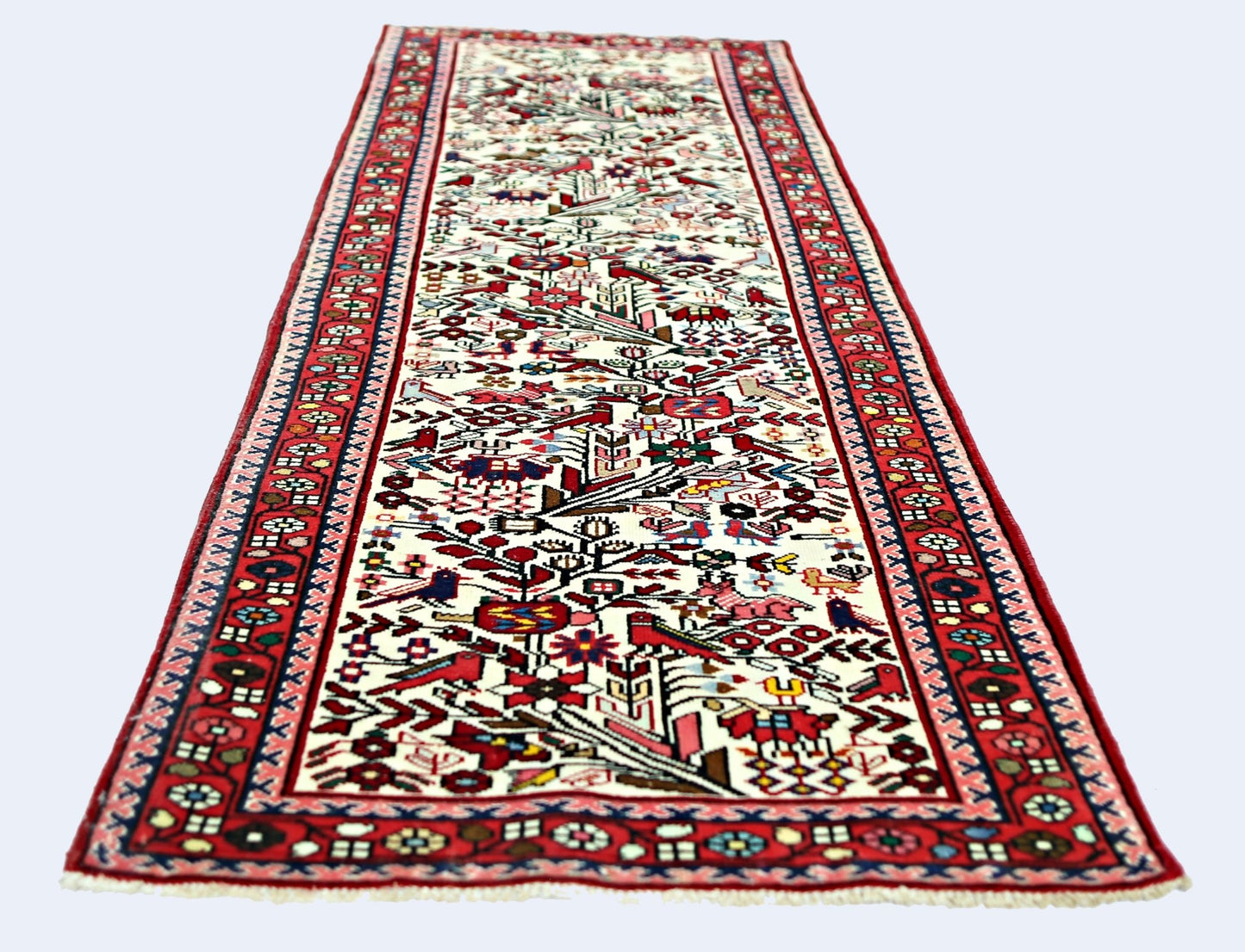 A vintage Persian runner rug featuring a cream field with intricate red and multi-colored motifs.