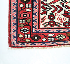 A corner view of a handmade vintage Persian runner featuring intricate floral patterns in red.