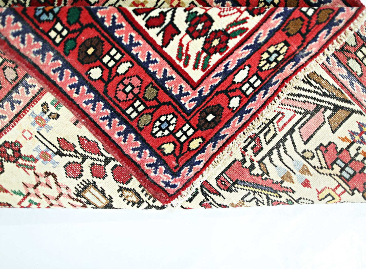 A folded vintage Persian runner featuring intricate floral patterns in red, blue, and cream.
