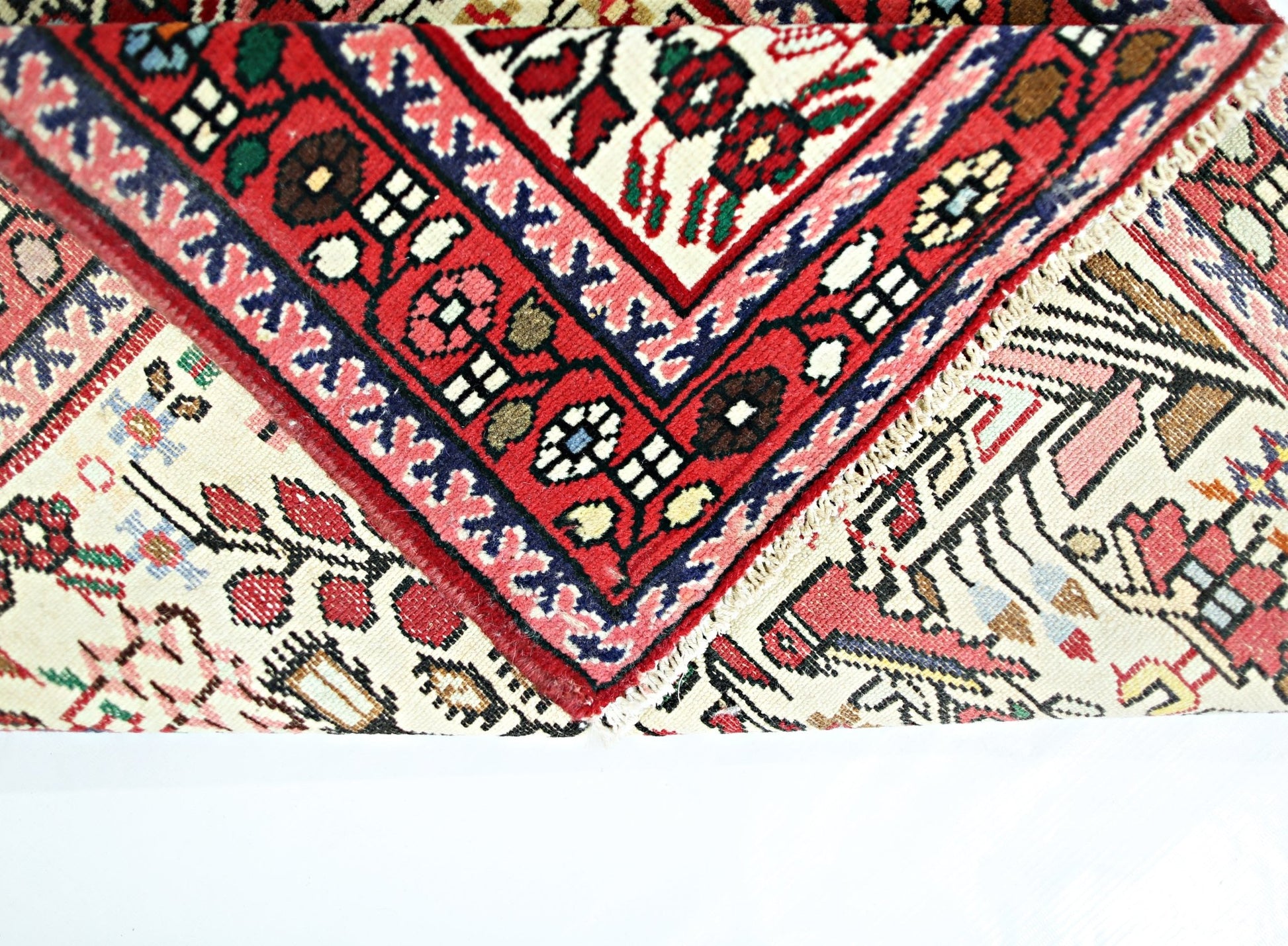 A folded vintage Persian runner featuring intricate floral patterns in red, blue, and cream.