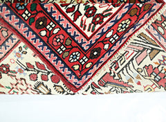 A folded vintage Persian runner featuring intricate floral patterns in red, blue, and cream.
