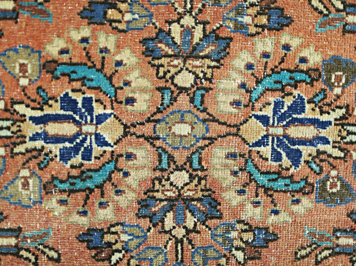 A close-up of a vintage Persian runner featuring a symmetrical floral pattern in blue and tan.