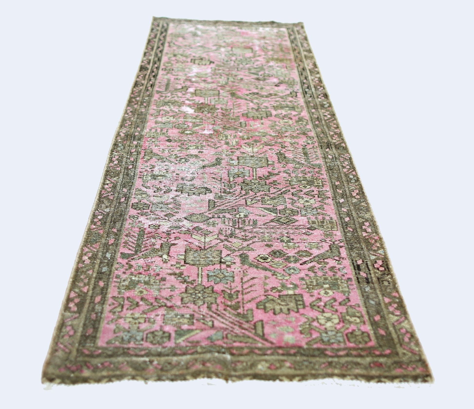 A vintage Persian runner rug featuring a faded pink field with intricate grey floral patterns.